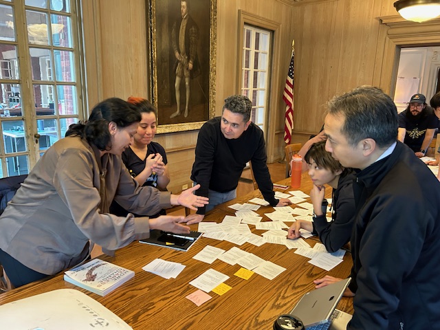 Small group standing at a table arranging and discussing pattern cards