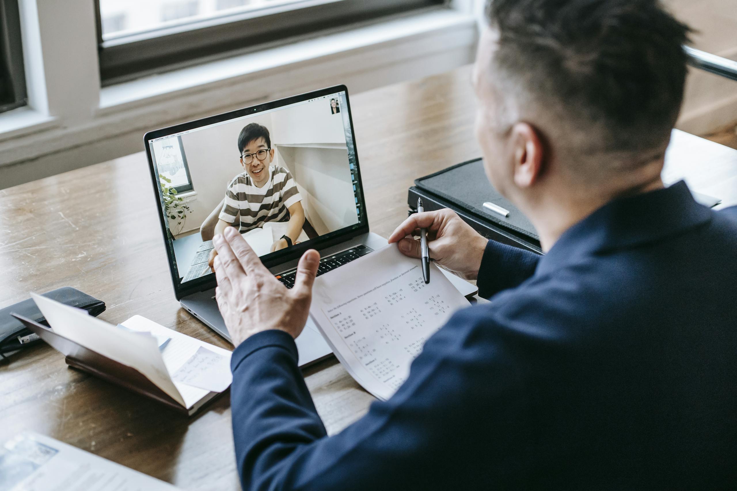 A person at a laptop with physical notes and a paper carrying on an online conversation
with an author