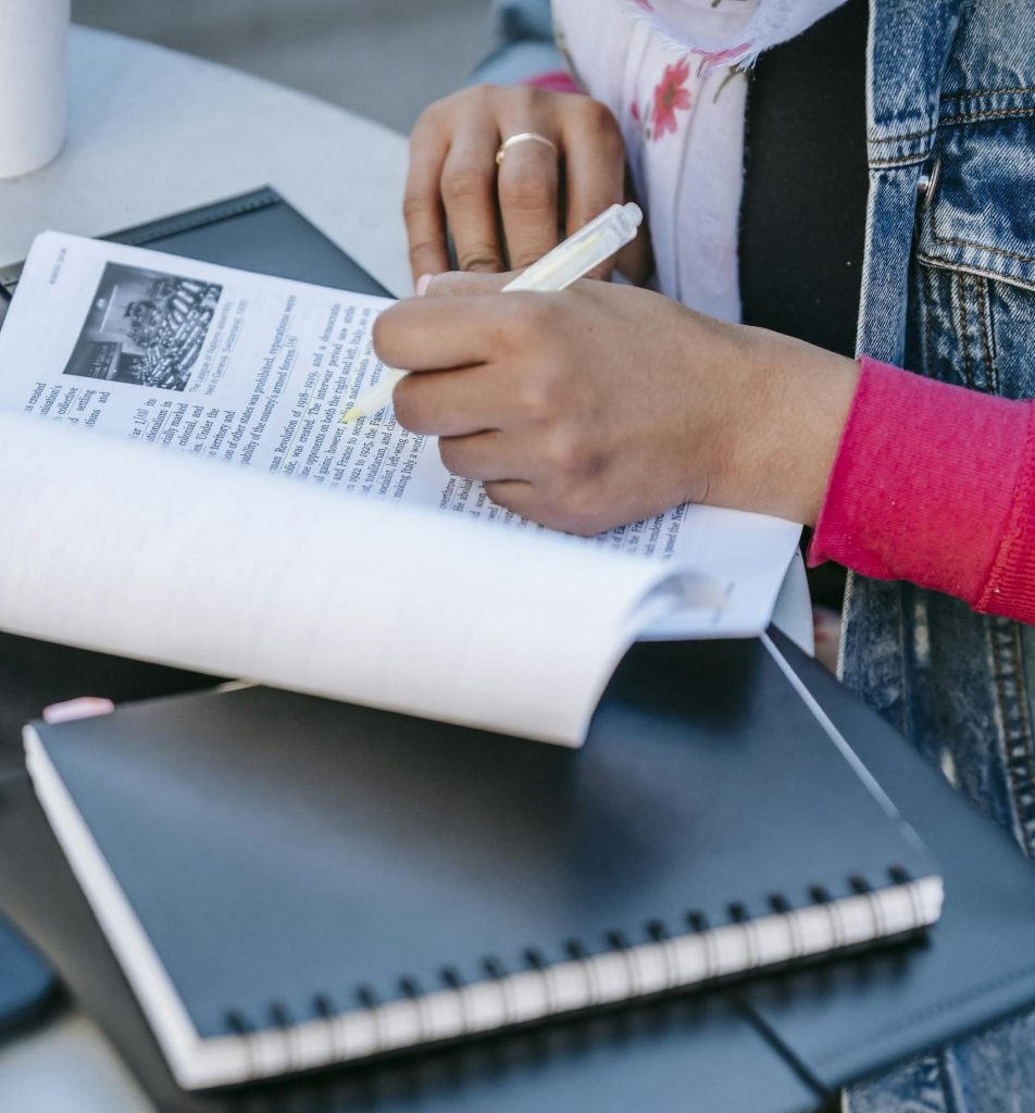 Person with yellow highlighter marking up a manuscript