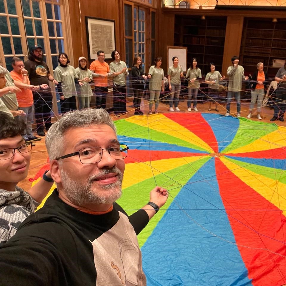 PLoP closing ceremony with colorful parachute on the floor and many strings of yarn
showing connections people made with each other