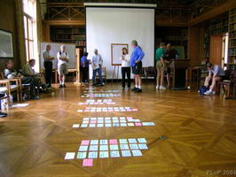 Sticky notes arranged on a hardwood floor with people standing or sitting nearby in a
bookshelf-lined room